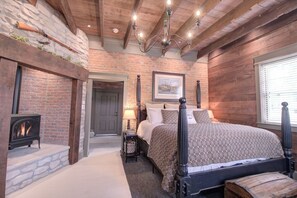 Cozy bedroom with a stone fireplace, four-poster bed, and chandelier.