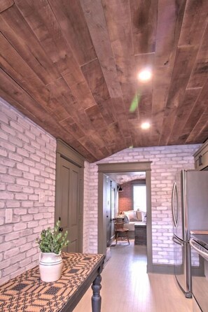 Enjoy cooking in this kitchen with exposed beams, brick wall, and a dining area with a wooden table.