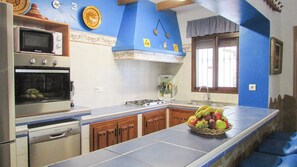 A kitchen with a microwave, oven, and sink. There is a fruit bowl on the counter.
