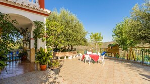 A patio area with a table and chairs, surrounded by potted plants and a fence. - Parador de los Olivos Sayalonga by Ruralidays (Málaga)
