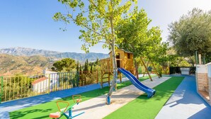 A playground with a slide, climbing structures, and a view of mountains in the background. - Parador de los Olivos Sayalonga by Ruralidays (Málaga)