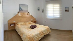 A bedroom with a wooden headboard, a bed with a floral bedspread, two bedside lamps, and a window with blinds. - Finca Mi Hogar Málaga - Churriana by Ruralidays (Málaga)