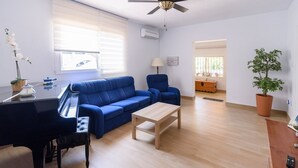 A living room with a blue sofa, a wooden coffee table, a blue armchair, a piano, and a potted plant. - Finca Mi Hogar Málaga - Churriana by Ruralidays (Málaga)