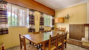 A dining room with a wooden table and chairs, a wooden cabinet, and a fireplace. - Sortes Ana Órgiva by Ruralidays (Granada)