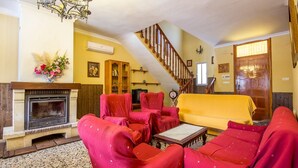A living room with a fireplace, red armchairs, a yellow sofa, and a staircase. - Sortes Ana Órgiva by Ruralidays (Granada)