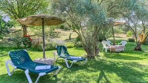 A garden with two lounge chairs, a table, and an umbrella. - La Monja Antequera - La Higuera by Ruralidays (Málaga)