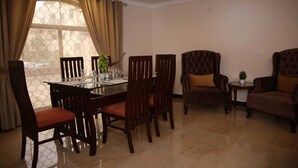 A dining area with a glass-top table, wooden chairs, and a chandelier. - Homewood Suites (Lahore)