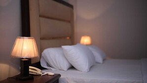A hotel room with a bed, a nightstand with a lamp, and a telephone. - Homewood Suites (Lahore)