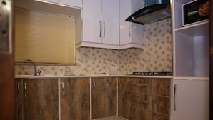 A kitchen with wooden cabinets, a stainless steel sink, and a microwave. - Homewood Suites (Lahore)