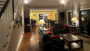 Un vaste salon avec un escalier, un coin repas et une cuisine à l’arrière-plan.