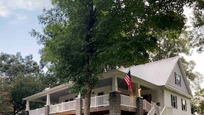 Une maison à deux étages dotée d’un porche couvert, de piliers en pierre et d’un drapeau.