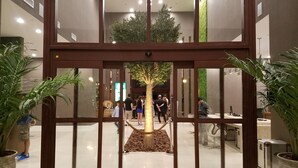 A hotel entrance with a revolving door, potted plants, and a visible indoor seating area with people. - 4 B/R Villa, Free Parking & Free Wi-Fi, Near Disney Family Friendly (Kissimmee)