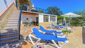 A pool area with lounge chairs, a staircase with patterned tiles, and a building with large windows.