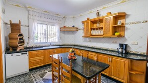 A kitchen with wooden cabinets, a black countertop, and a dining table with chairs.