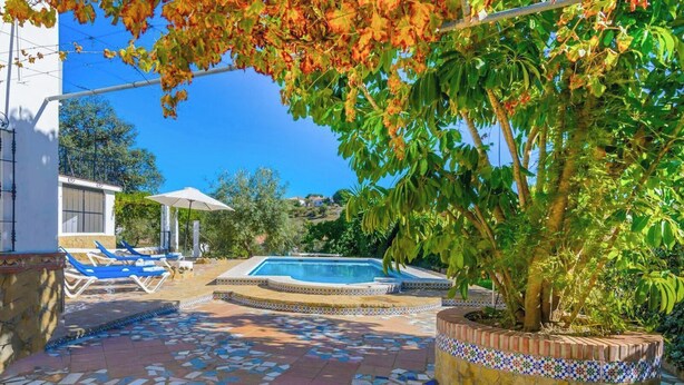 A swimming pool with lounge chairs and a tiled patio.