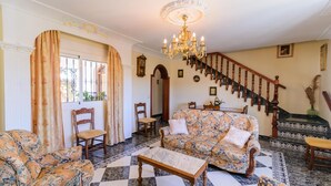 A living room with a patterned sofa, a coffee table, and a staircase with wooden railings.