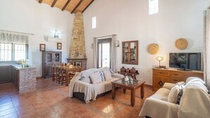 A spacious living area with a fireplace, a dining table, and a cozy seating arrangement. - Vistahermosa del Gastor by Ruralidays (Cádiz)