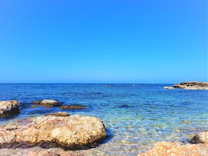 A clear blue sea with rocky shores and a distant sailboat. - Spectacular villa with pool and private tennis court150 meters from the sea (Dénia)