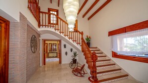 Een statige trap met houten balustrade en een grote kroonluchter.