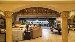 A spacious living area with a view of the ocean, featuring a fireplace, comfortable seating, and a dining area with a view. - Poolside Bliss Awaits, Cabo San Lucas Villa 1006 (Cabo San Lucas)