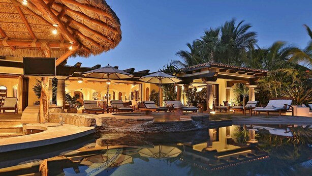 A luxurious resort with a swimming pool, lounge chairs, and a thatched-roof structure. - Poolside Bliss Awaits, Cabo San Lucas Villa 1006 (Cabo San Lucas)