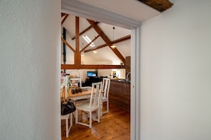 A dining area with a wooden table and chairs, a television, and a kitchen area with a sink and countertop.