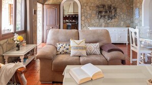Una sala de estar acogedora con un sofá color beige, una mesa de centro y un comedor con mobiliario blanco.