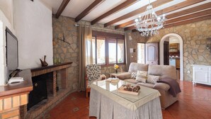 Una sala de estar acogedora con chimenea, paredes de piedra, un sofá y una mesa de centro.