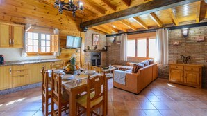 Ein geräumiger Wohnbereich mit Esstisch und Stühlen aus Holz, einer Couch und einem Kamin.