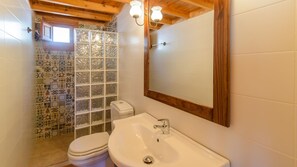 Une salle de bain avec une douche carrelée, un lavabo blanc et des toilettes.