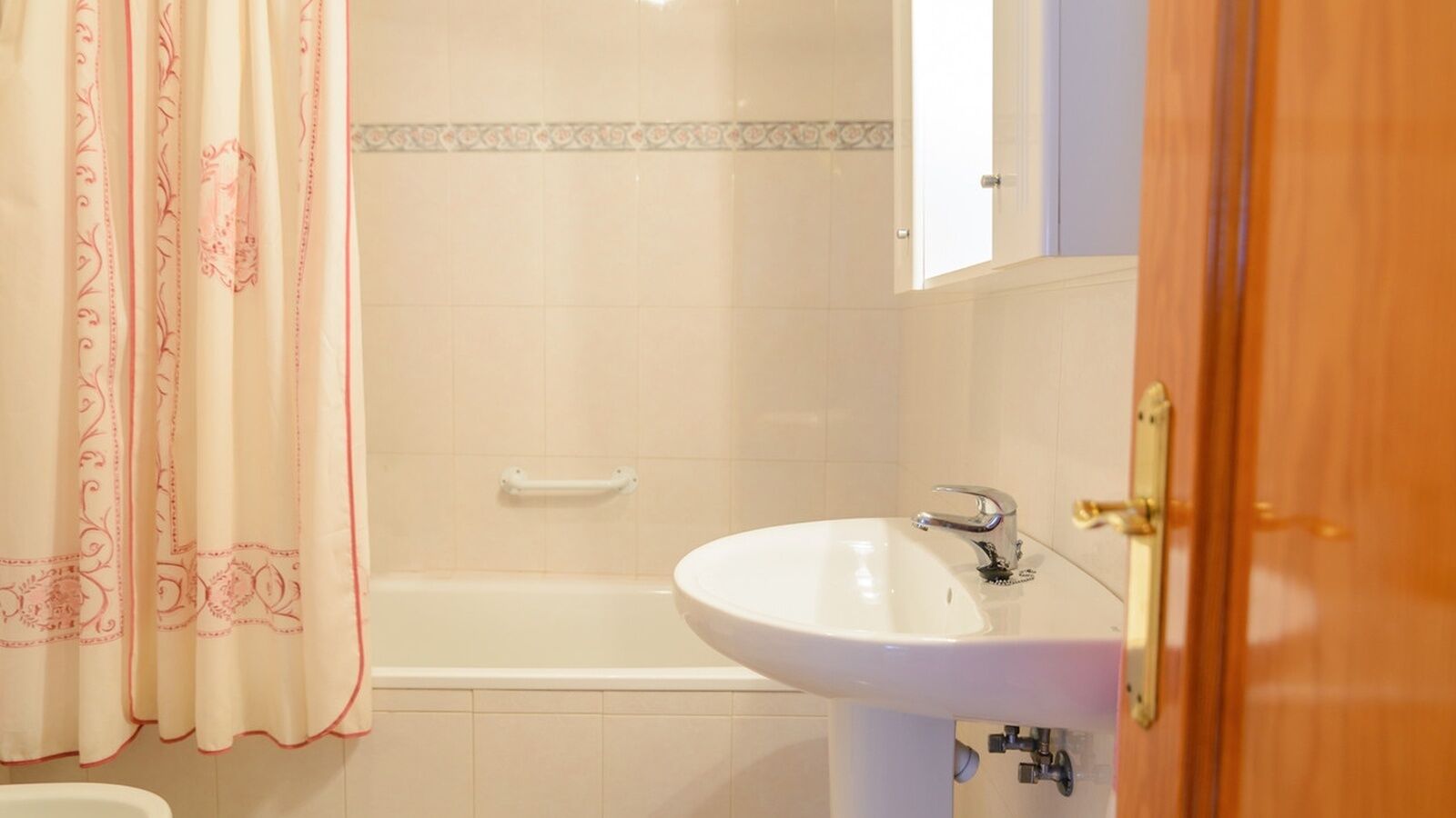 A bathroom with a bathtub, a sink, and a shower curtain.