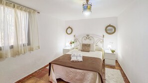 Une chambre d’hôtel avec un lit, des tables de chevet, une lampe, un miroir et une fenêtre avec des rideaux.