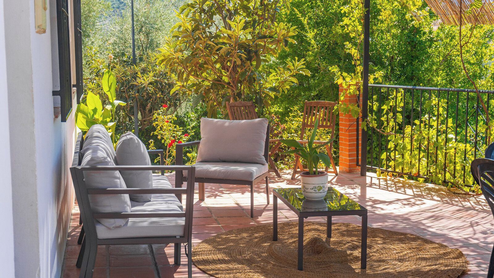 Une terrasse avec deux chaises, une table et un pot de fleurs.