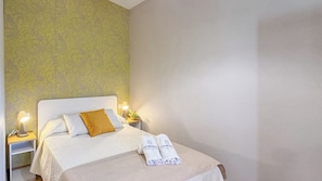 A hotel room with a bed, two bedside lamps, a nightstand, and a wall with a patterned wallpaper. - Casa Madrona Periana by Ruralidays (Málaga)