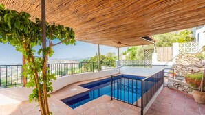 Uma área de piscina privativa com design curvo, cercada por um muro de pedra e uma grade de metal.