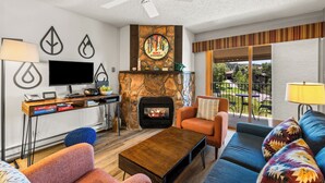A modern living room with a fireplace, a television, and a sofa. - Ski Inn 1-Bedroom Retreat with Hot Tub Access! (Steamboat Springs)