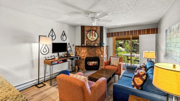 A living room with a fireplace, a sofa, a coffee table, and a TV. - Ski Inn 1-Bedroom Retreat with Hot Tub Access! (Steamboat Springs)
