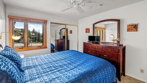 Ein Schlafzimmer mit Bett, Kommode und Deckenventilator.