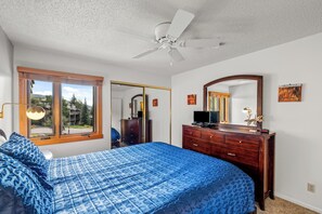 Een slaapkamer met een bed, een ladekast en een plafondventilator.