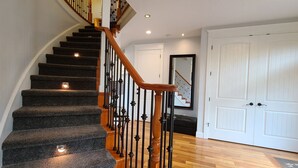 A staircase with carpeted steps, wooden handrails, and black metal railings. - Beautiful Home with Ocean View, Large Yard, and Hot Tub  (Lincoln City)