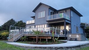 A two-story house with a balcony and a small deck area. - Beautiful Home with Ocean View, Large Yard, and Hot Tub  (Lincoln City)