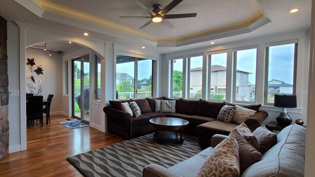 A spacious living room with a fireplace, large windows, and a ceiling fan. - Beautiful Home with Ocean View, Large Yard, and Hot Tub  (Lincoln City)
