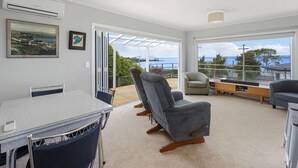 A modern living room with a dining area, large windows, and a view of the sea. - I See The Lake - Omori Holiday Home (Omori)