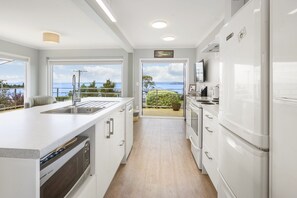 A modern kitchen with a large island, built-in appliances, and a view of the outdoors.