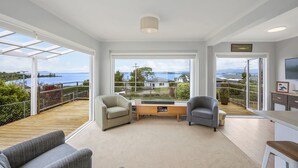 A spacious balcony with a wooden deck, two armchairs, a small table, and a TV. - I See The Lake - Omori Holiday Home (Omori)