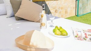A sunlit outdoor seating area with a table, a bottle, glasses, and a hat. - Cortijo La Jirafa Torrox by Ruralidays (Málaga)