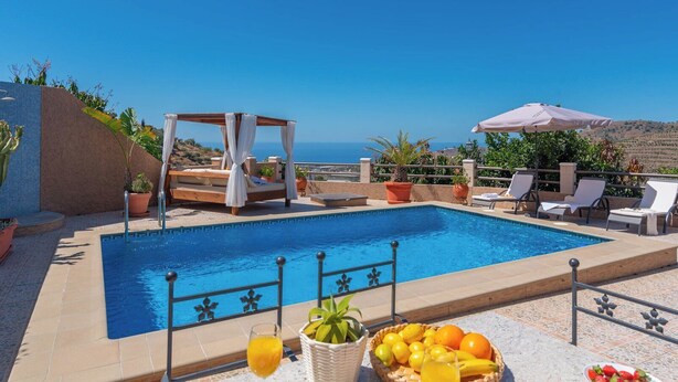 A pool area with a pergola, lounge chairs, and a view of the sea. - Villa Mi Paraíso Torrox by Ruralidays (Málaga)