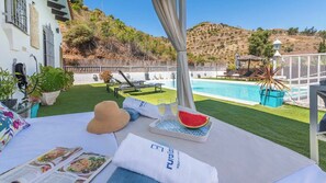 A poolside lounge area with a bed, sun loungers, and a pool. - Villa Omairi Torrox by Ruralidays (Málaga)