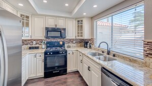 A modern kitchen with white cabinetry, a black stove, a microwave, and a sink. - Modern & Cozy | 13min to Strip, ♛Royal Beds, Pool (Henderson)