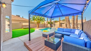 An outdoor patio with a pool, blue furniture, and a covered area. - Modern & Cozy | 13min to Strip, ♛Royal Beds, Pool (Henderson)